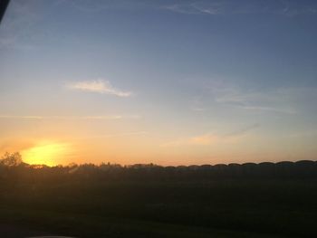 Scenic view of silhouette field against sky during sunset