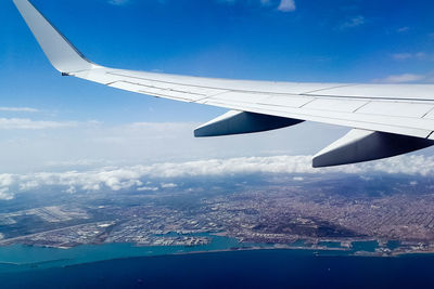 Aerial view of airplane flying over landscape against sky