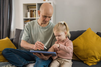 Young woman using digital tablet while sitting on sofa at home