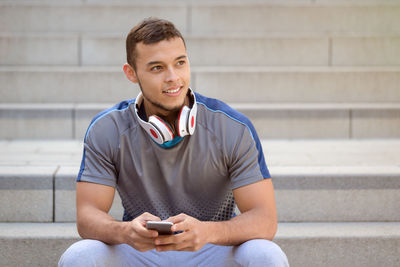 Young man using mobile phone while sitting on staircase