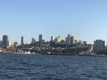 Sea by buildings against clear sky