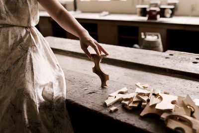 Cropped image of woman holding wooden piece at workshop