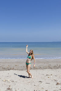 Happy woman in bikini standing on shore at beach