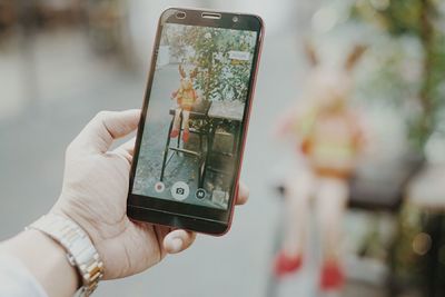 Close-up of hand using mobile phone outdoors