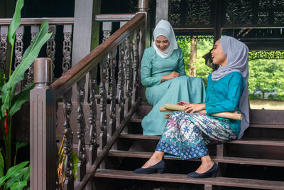 Rear view of women sitting on railing