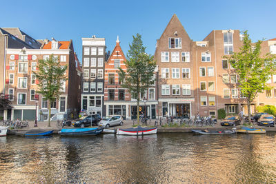 Boats moored on canal by buildings in city