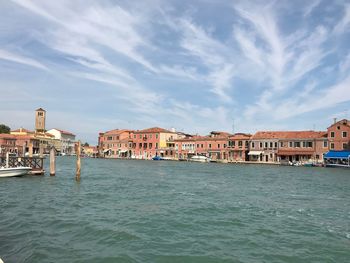 View of buildings at waterfront against cloudy sky