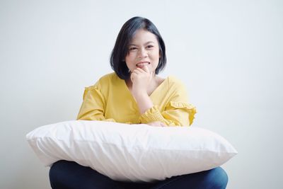 Portrait of a smiling young woman sitting against white background