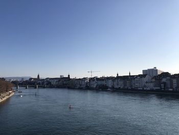 View of buildings by sea against clear blue sky