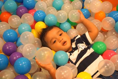 Portrait of boy lying amidst balloons