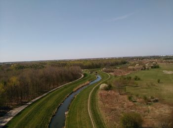 Panoramic shot of road amidst field against clear sky