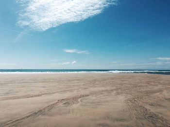 Scenic drone view of beach and ocean against blue sky