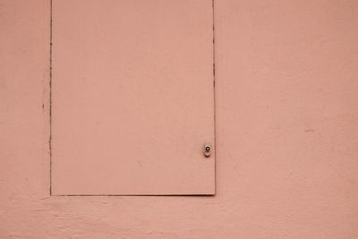 Full frame shot of coral colored door on wall