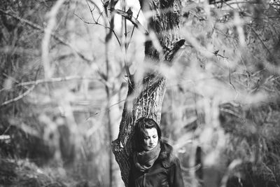 Portrait of woman standing by tree in forest