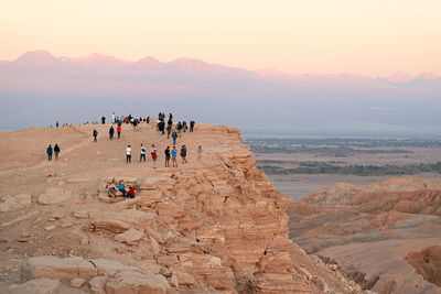 Visitors on the cliff waiting for sunset at valle de la luna or moon valley in atacama desert, chile