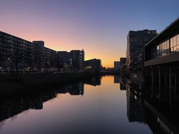 River amidst buildings against clear sky at sunset