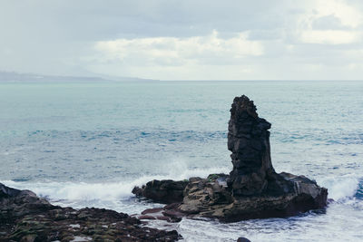 Scenic view of rocks in sea against sky