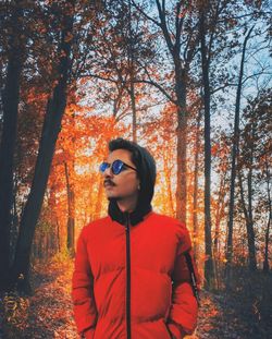 Boy wearing sunglasses while standing against trees in forest during autumn