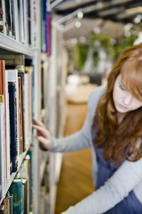 Young woman choosing book in library