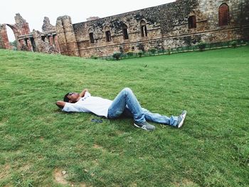 High angle view of man lying on grass near old ruins