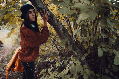 Portrait of young woman standing against plants