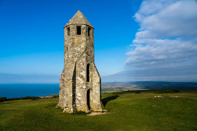 Old ruins of building on field against sky