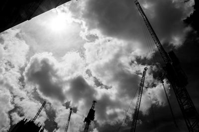 Low angle view of crane against cloudy sky