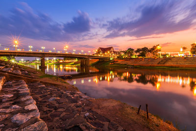 Illuminated bridge over river against sky at night