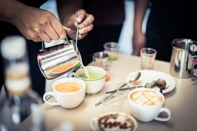 High angle view of barista mixing milk in drink at cafe