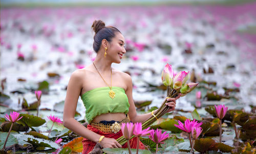 Woman holding pink flower in lake