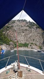 Sailboat sailing on sea by mountain against sky