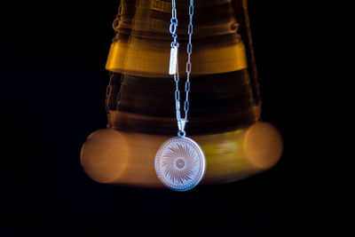 Close-up of illuminated lighting equipment hanging against black background