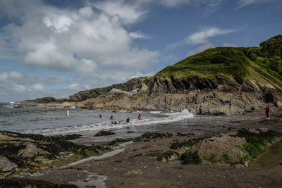 Scenic view of beach surrounded by rocky coastline against blue sky in devon, uk