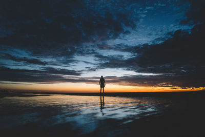 Silhouette man standing on beach against sky during sunset