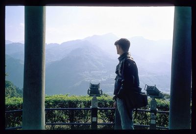 Side view of man looking at mountain range against sky