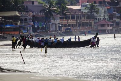 People pushing boat in sea 