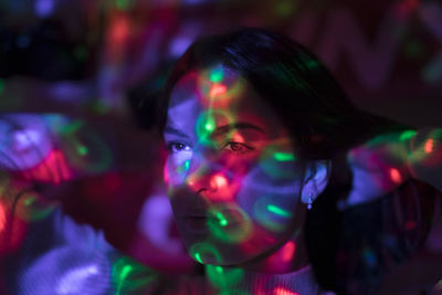 Close-up of colorful lights falling on woman face