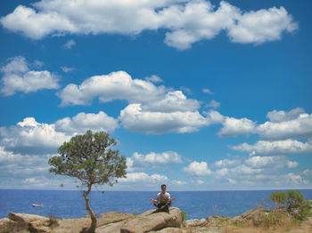 Man meditating on a rock with the ocean behindp