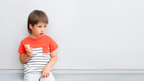 Portrait of cute girl standing against wall