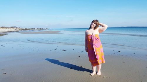 Woman standing at beach against sky