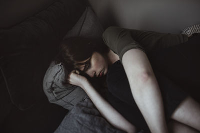 Depressed young woman lying on bed