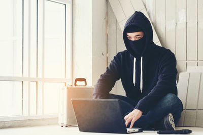 Burglar using laptop with gun on floor