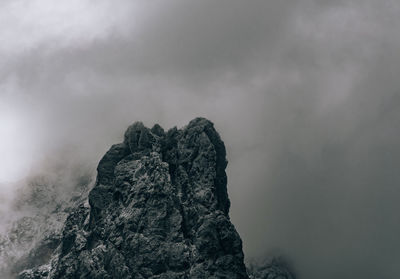 Rocky mountain peak shrouded in grey clouds and mist