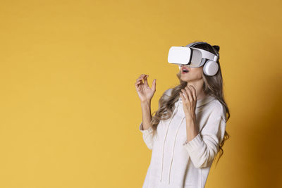 Portrait of young woman wearing sunglasses while standing against yellow background