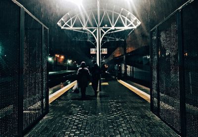 People walking on railroad station platform at night