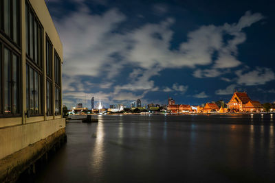 City at waterfront against cloudy sky