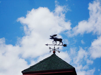 Low angle view of weather vane against cloudy sky