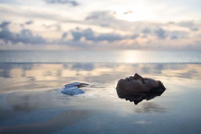 Woman into a infinity swimming pool near the ocean