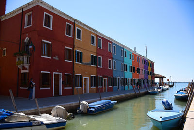 Boats moored on canal by buildings against sky in city