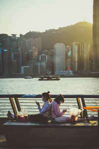 People sitting on promenade against buildings in city